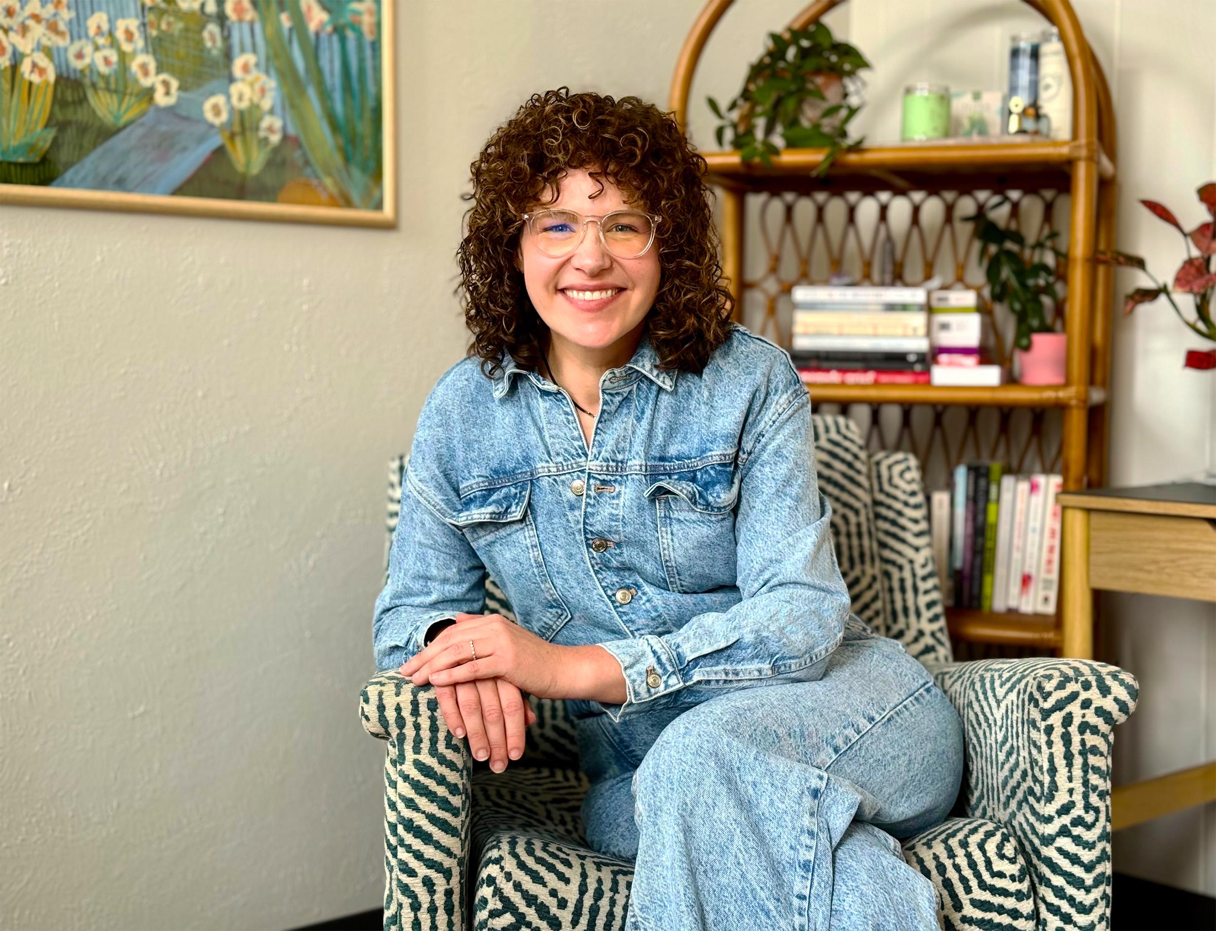 Portrait of Abby Howard smiling in a plant-filled reading nook